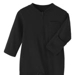 Close-up of the black romper: fabric guard at the top of the zip, chest pocket and fold-over hand cuff