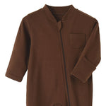 Close-up of the brown romper: fabric guard at the top of the zip, chest pocket and fold-over hand cuff