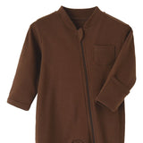 Close-up of the brown romper: fabric guard at the top of the zip, chest pocket and fold-over hand cuff