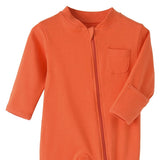 Close-up of the orange romper: fabric guard at the top of the zip, chest pocket and fold-over hand cuff