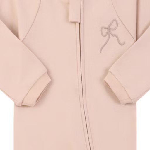 Close-up of the dusty pink embroidered bow print, the cotton jersey and the zip