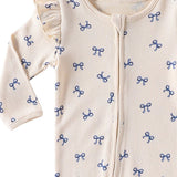 Close-up of the shoulder frill, rib texture and the top of the zip on the Cream Bows romper