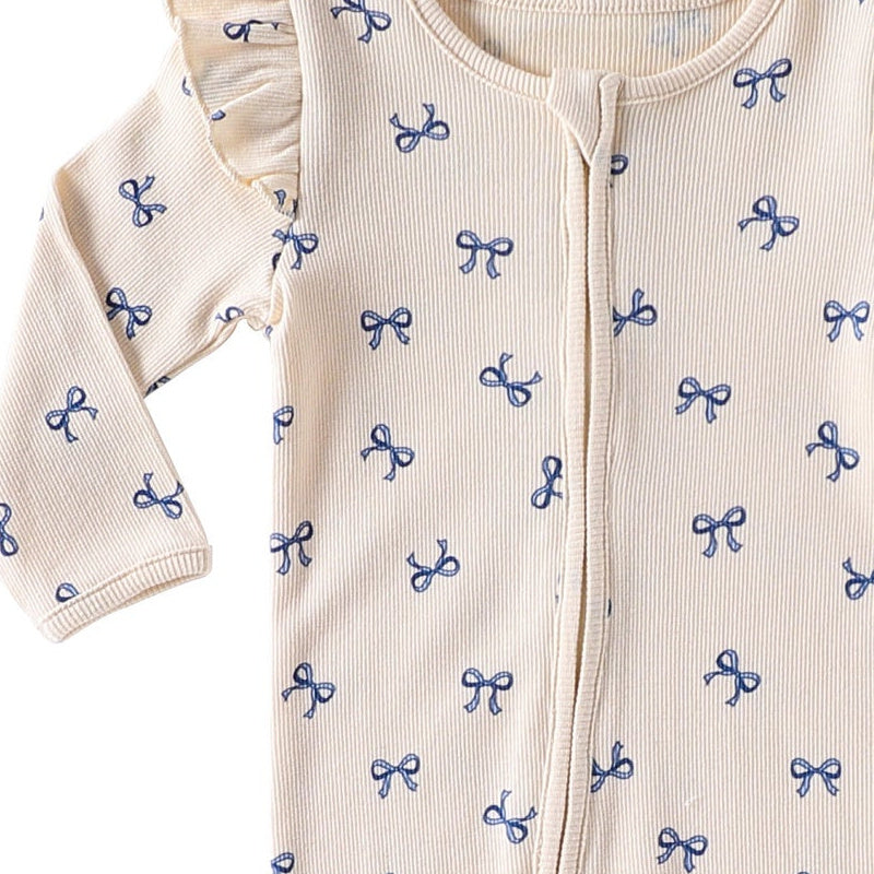 Close-up of the shoulder frill, rib texture and the top of the zip on the Cream Bows romper