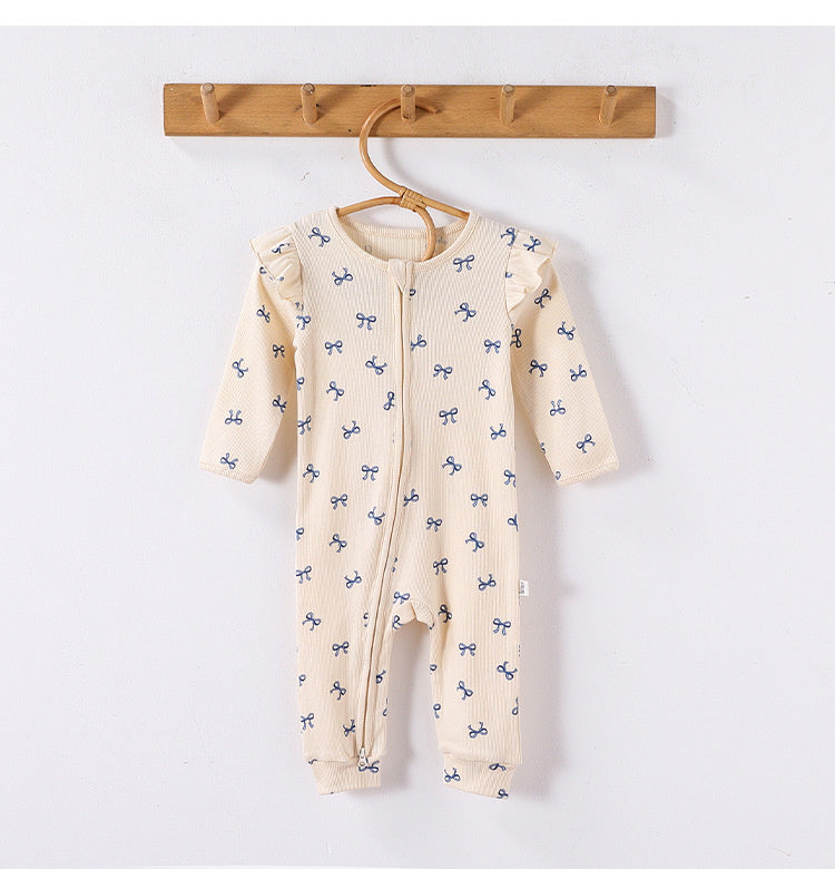 Cream Bows frill-shoulder romper on a wooden hanger, front view showing the zip down one leg and the ankle cuffs