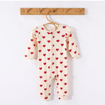 Cream Hearts frill-shoulder romper on a wooden hanger, front view showing the zip down one leg and the ankle cuffs