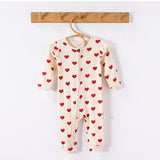 Cream Hearts frill-shoulder romper on a wooden hanger, front view showing the zip down one leg and the ankle cuffs