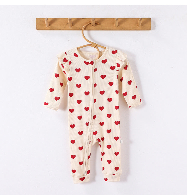 Cream Hearts frill-shoulder romper on a wooden hanger, front view showing the zip down one leg and the ankle cuffs