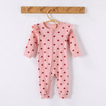 Pink Hearts frill-shoulder romper on a wooden hanger, front view showing the zip down one leg and the ankle cuffs