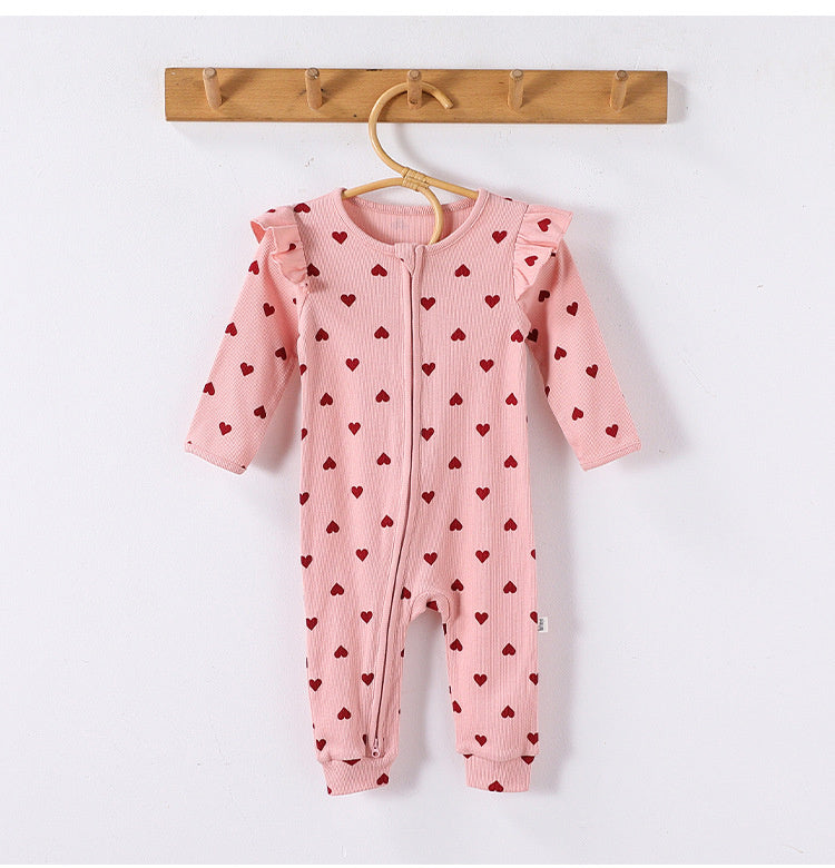 Pink Hearts frill-shoulder romper on a wooden hanger, front view showing the zip down one leg and the ankle cuffs