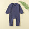 Navy ribbed baby romper with a zip from the neck to one ankle and fold-over cuffs, laid flat