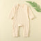 Pale Apricot ribbed baby romper with a zip from the neck to one ankle and fold-over cuffs, laid flat