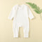 White ribbed baby romper with a zip from the neck to one ankle and fold-over cuffs, laid flat