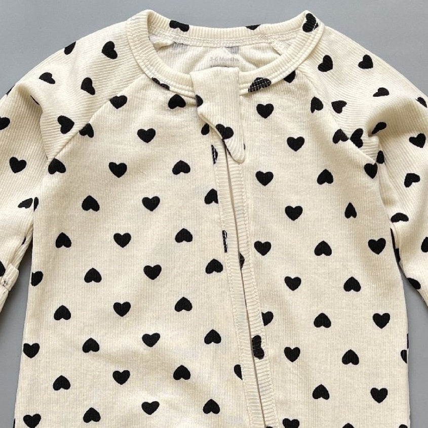 Close-up of the cream heart print, the rib knit and the top of the zip