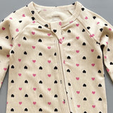 Close-up of the cream pink heart print, the rib knit and the top of the zip