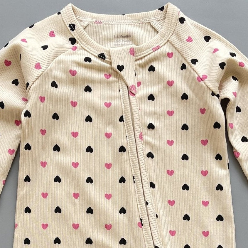 Close-up of the cream pink heart print, the rib knit and the top of the zip