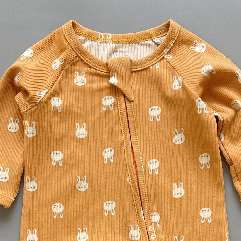Close-up of the orange bunny print, the rib knit and the top of the zip