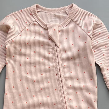 Close-up of the pink red spot print, the rib knit and the top of the zip