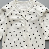 Close-up of the white black star print, the rib knit and the top of the zip