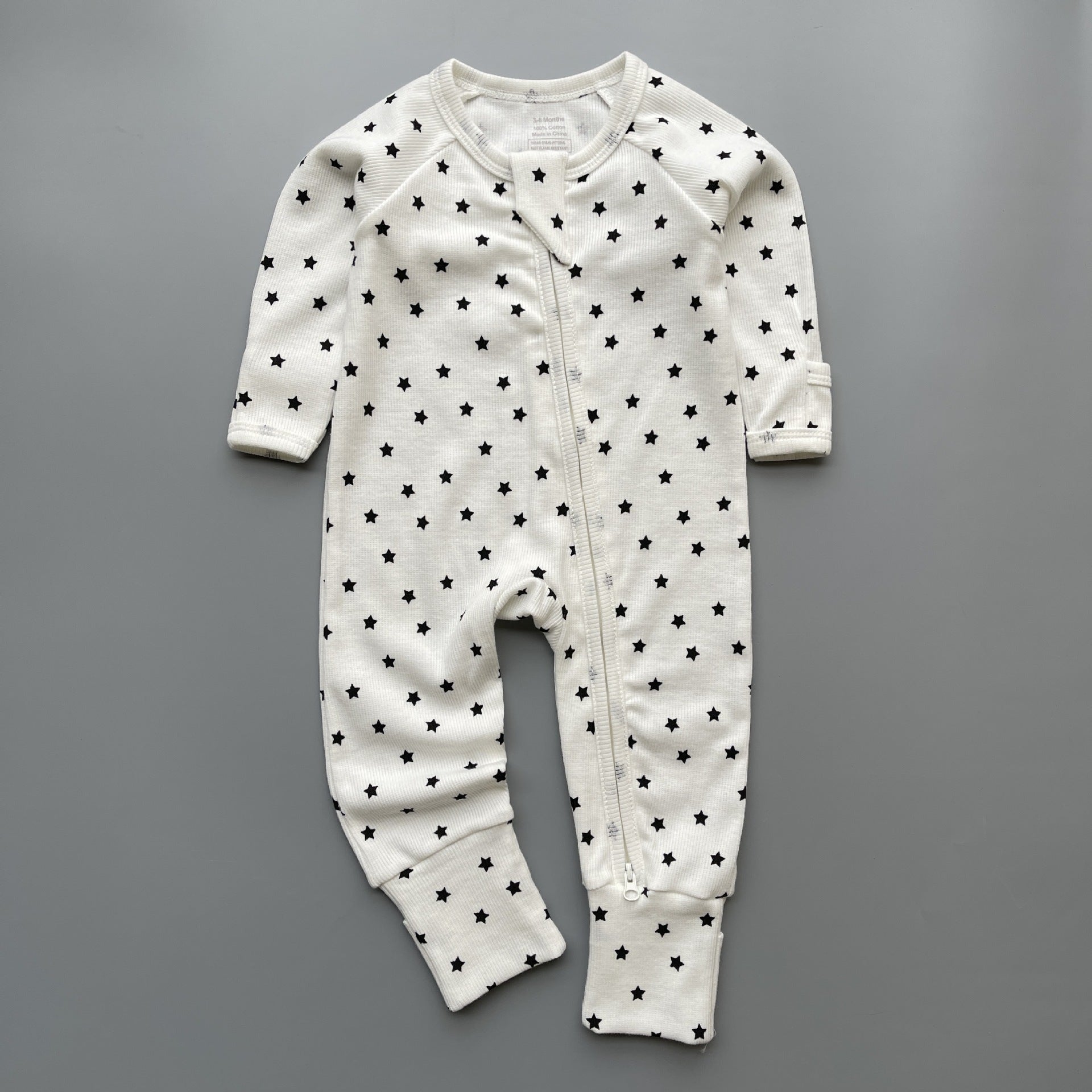 White black star ribbed zip baby sleepsuit with fold-over hand and foot cuffs, laid flat