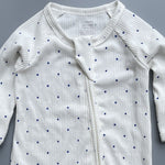 Close-up of the white navy spot print, the rib knit and the top of the zip