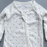 Close-up of the white navy spot print, the rib knit and the top of the zip
