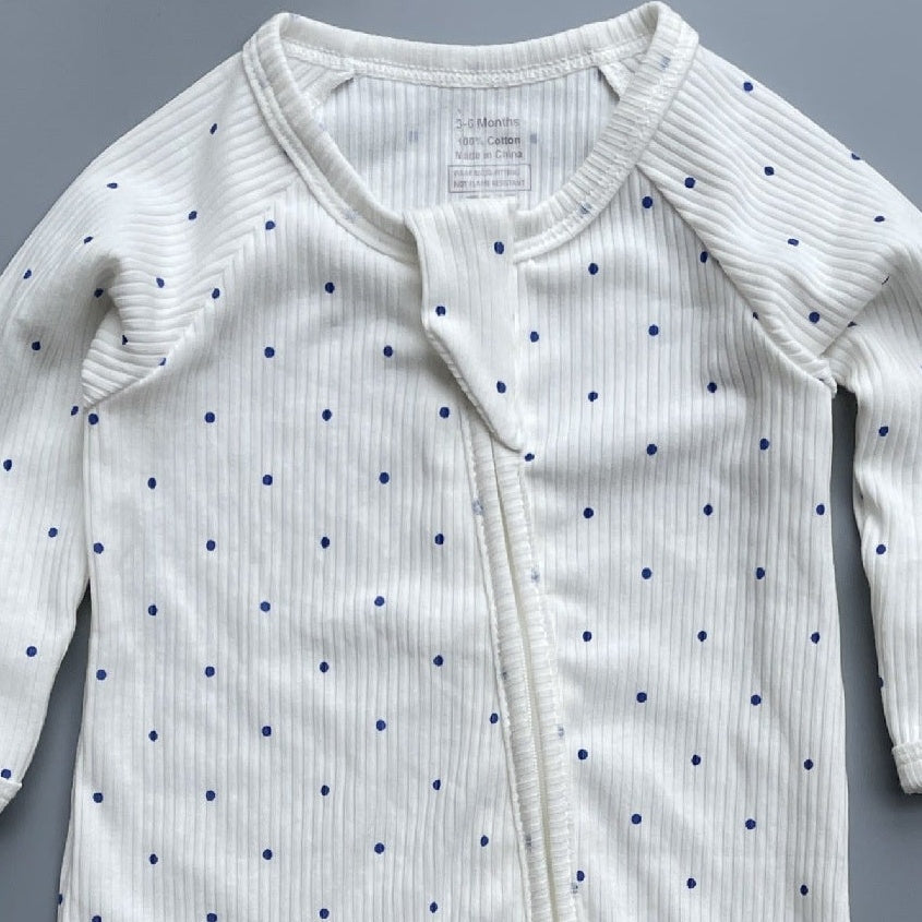 Close-up of the white navy spot print, the rib knit and the top of the zip