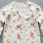 Close-up of the white rose print, the rib knit and the top of the zip