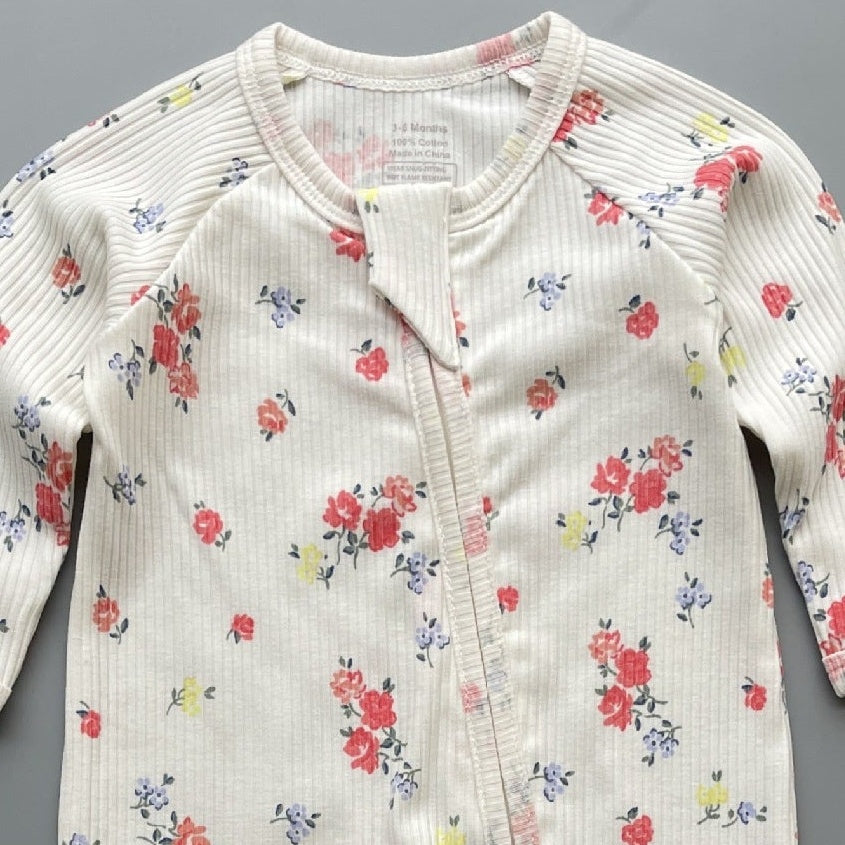Close-up of the white rose print, the rib knit and the top of the zip