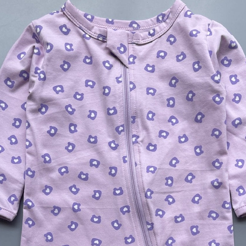 Close-up of the purple bear-head print on lilac jersey and the top of the zip