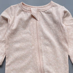 Close-up of the peach floral print, the cotton jersey and the top of the zip