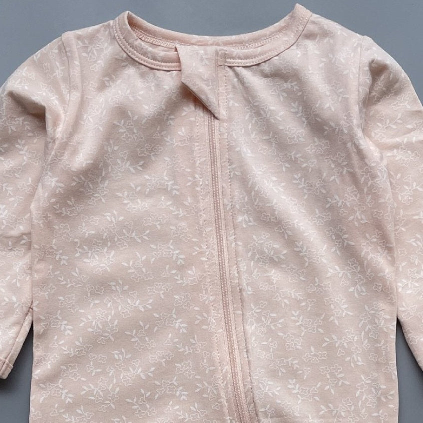 Close-up of the peach floral print, the cotton jersey and the top of the zip