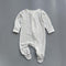 White navy polka dot zip baby sleepsuit with covered feet and fold-over hand cuffs, laid flat